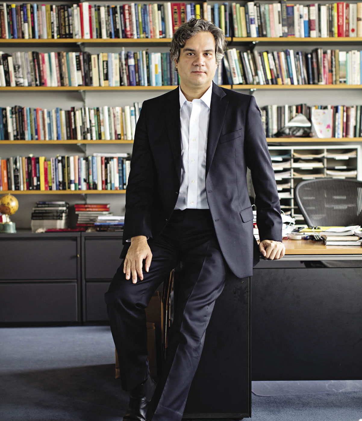 Man leaning against desk in front of bookshelves