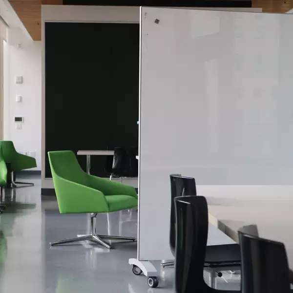 an empty room of green and black chairs, tables, and whiteboards